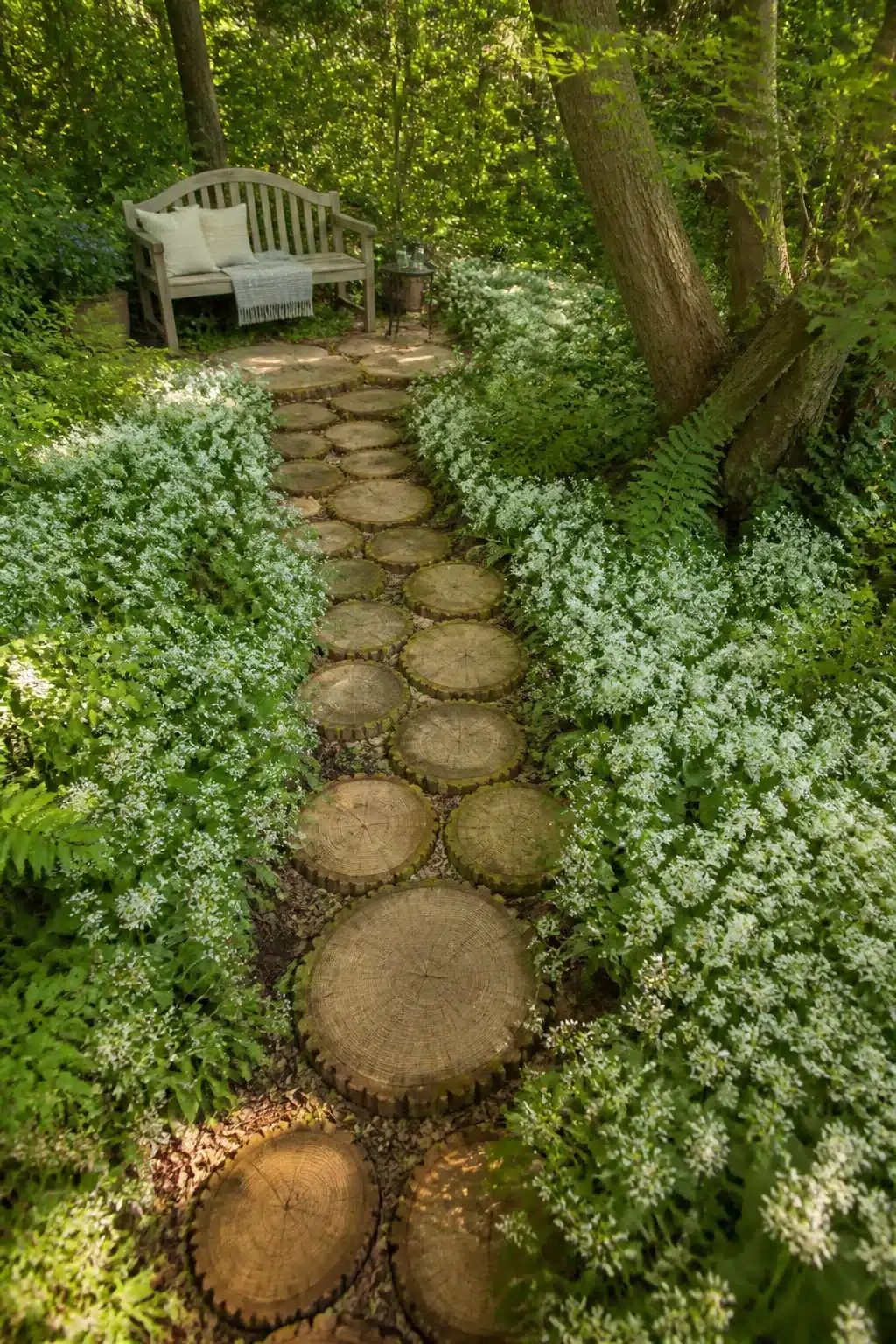 Log slice stepping stone path through sweet woodruff flowers — woodland garden paths with flowers idea