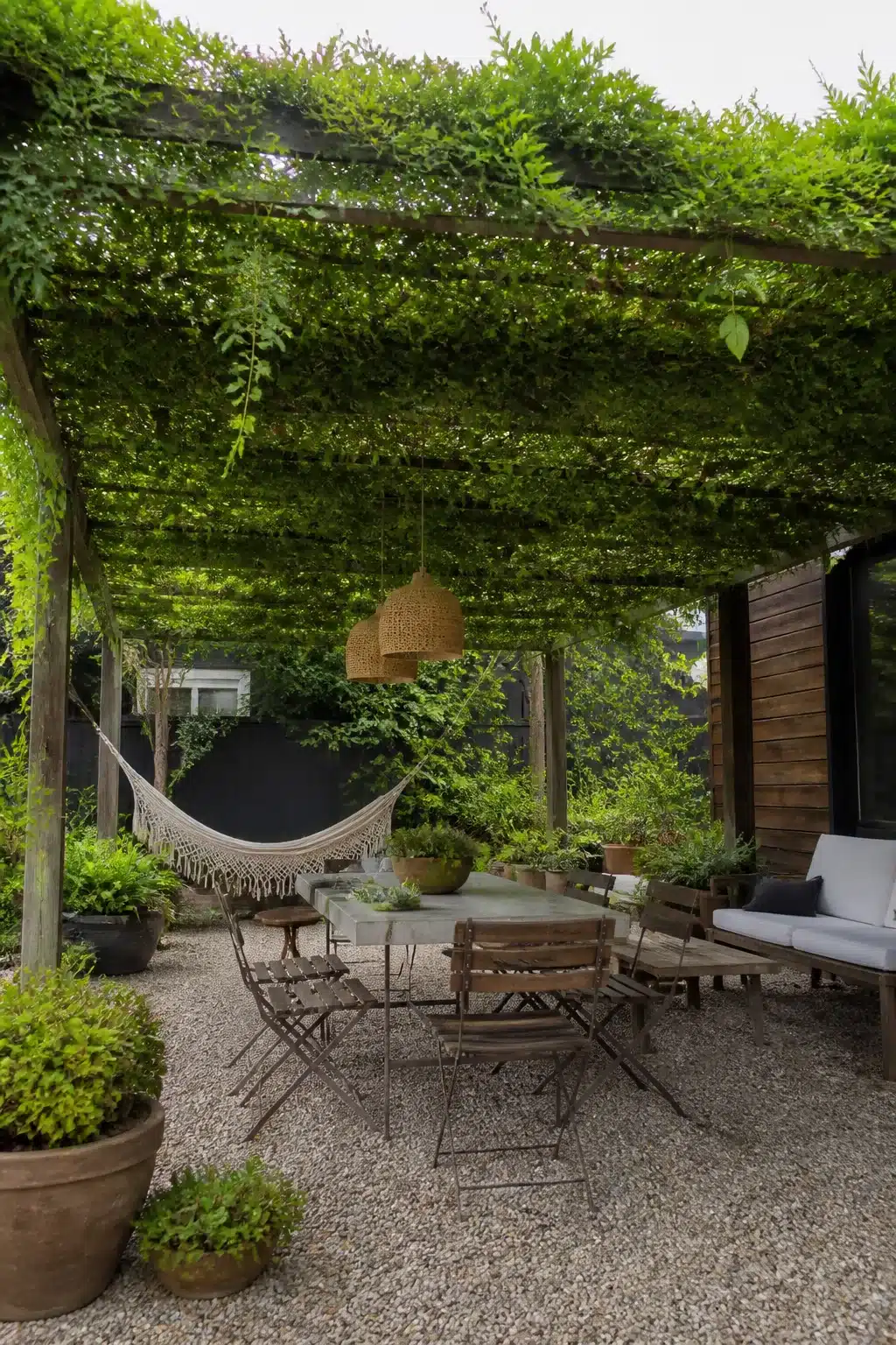Vine-covered pergola with gravel patio and hammock — backyard shade ideas using a living green canopy
