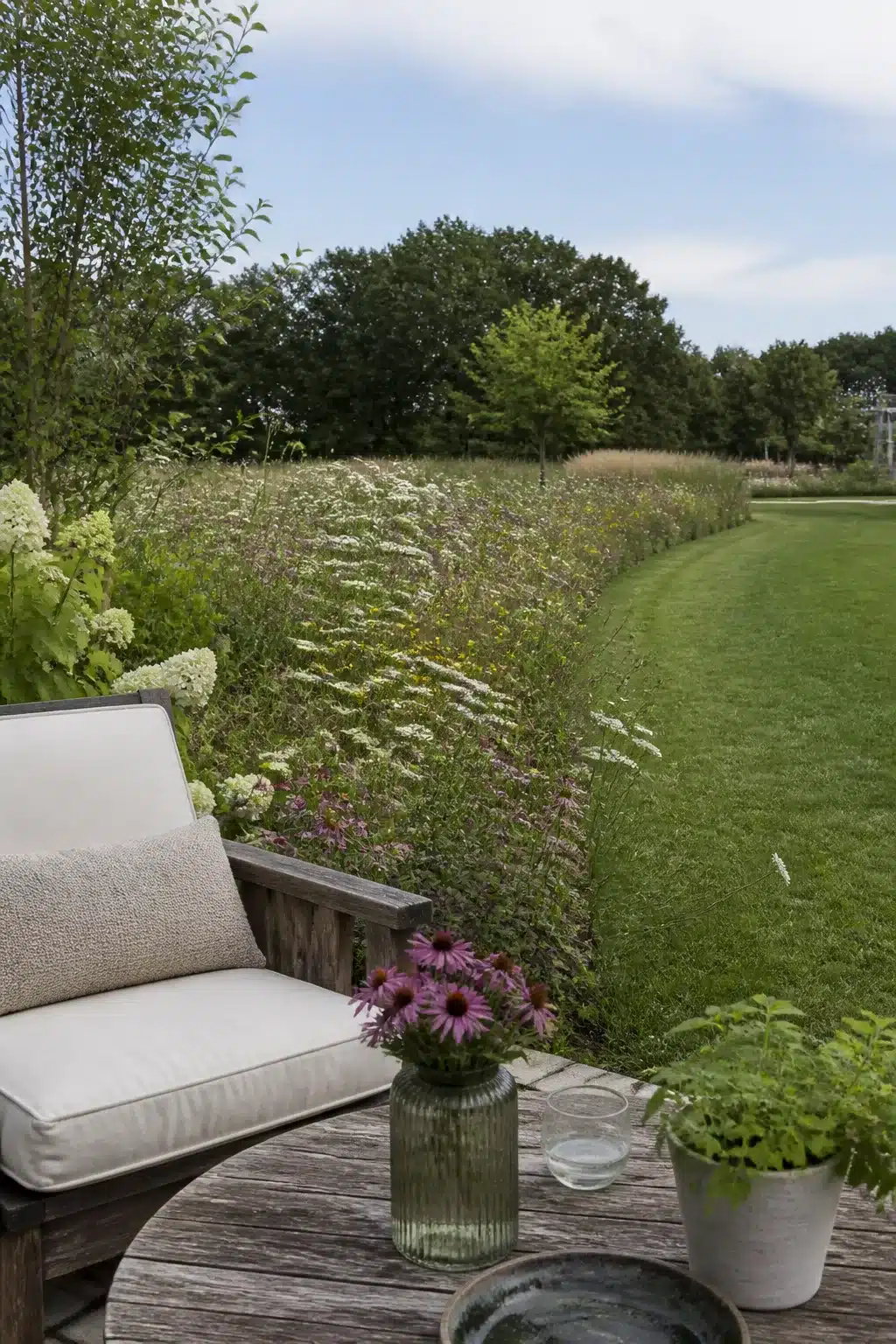 Wildflower border alongside manicured lawn in a large backyard landscaping idea with deck seating area