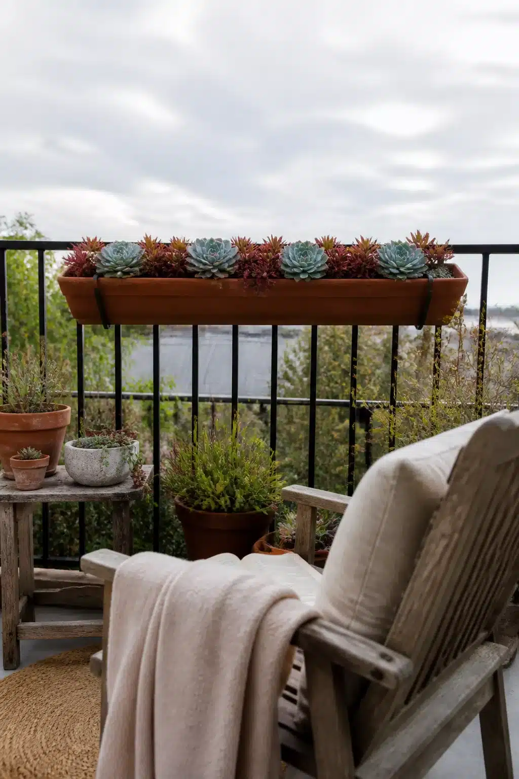 Rail-hung terracotta window box with succulent rosettes on a balcony — outdoor succulent garden pots idea