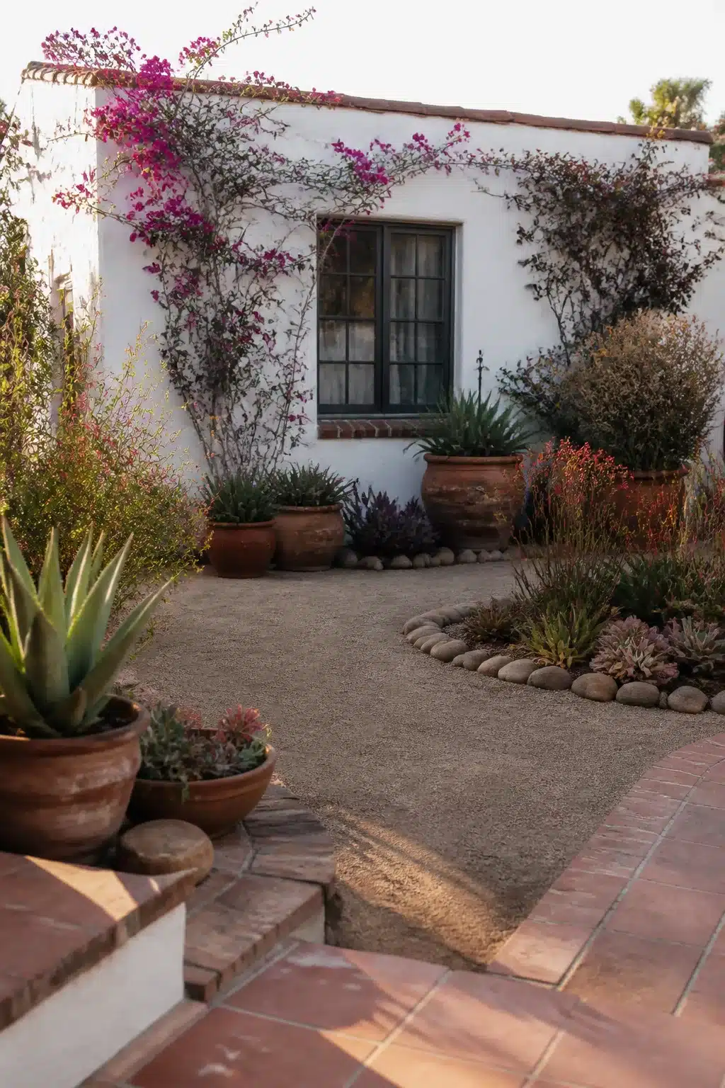 Spanish mission xeriscape front yard with bougainvillea, terra cotta urns, succulents, and decomposed granite — drought-tolerant design