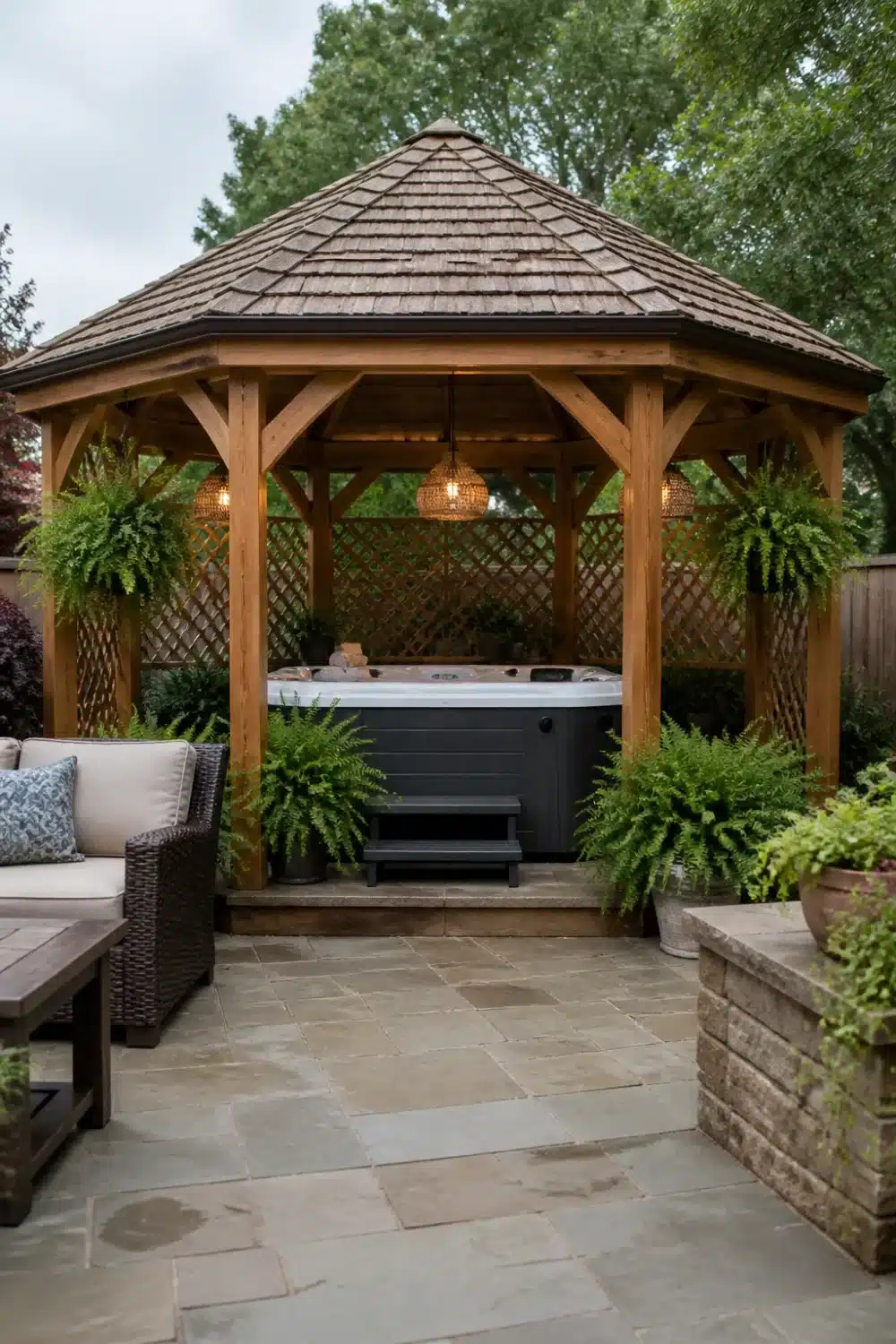 Cedar gazebo with shingle roof over a gray hot tub — backyard patio designs with hot tub and pendant lights