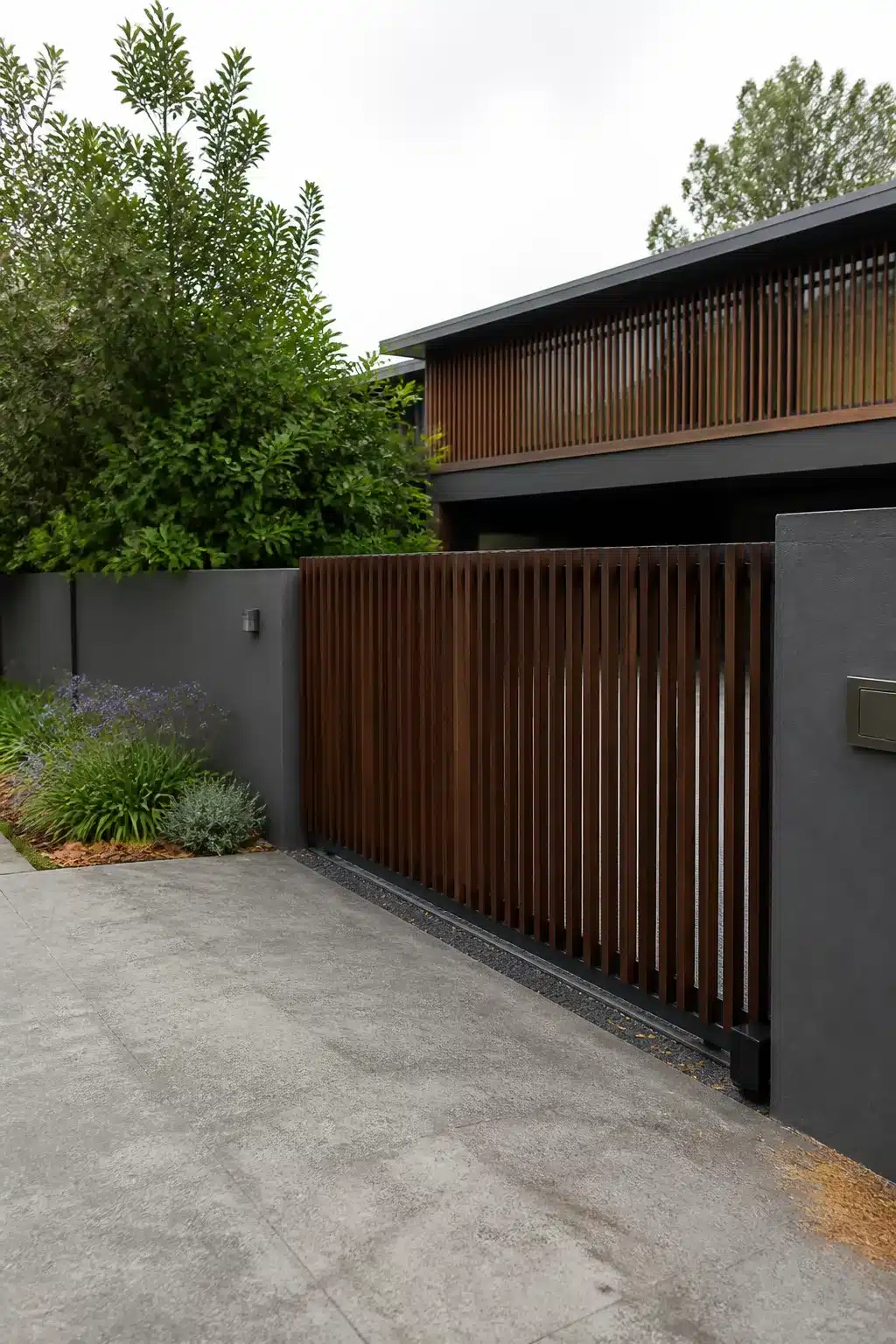 Dark timber vertical slat sliding driveway gate with charcoal rendered wall — modern driveway gate ideas