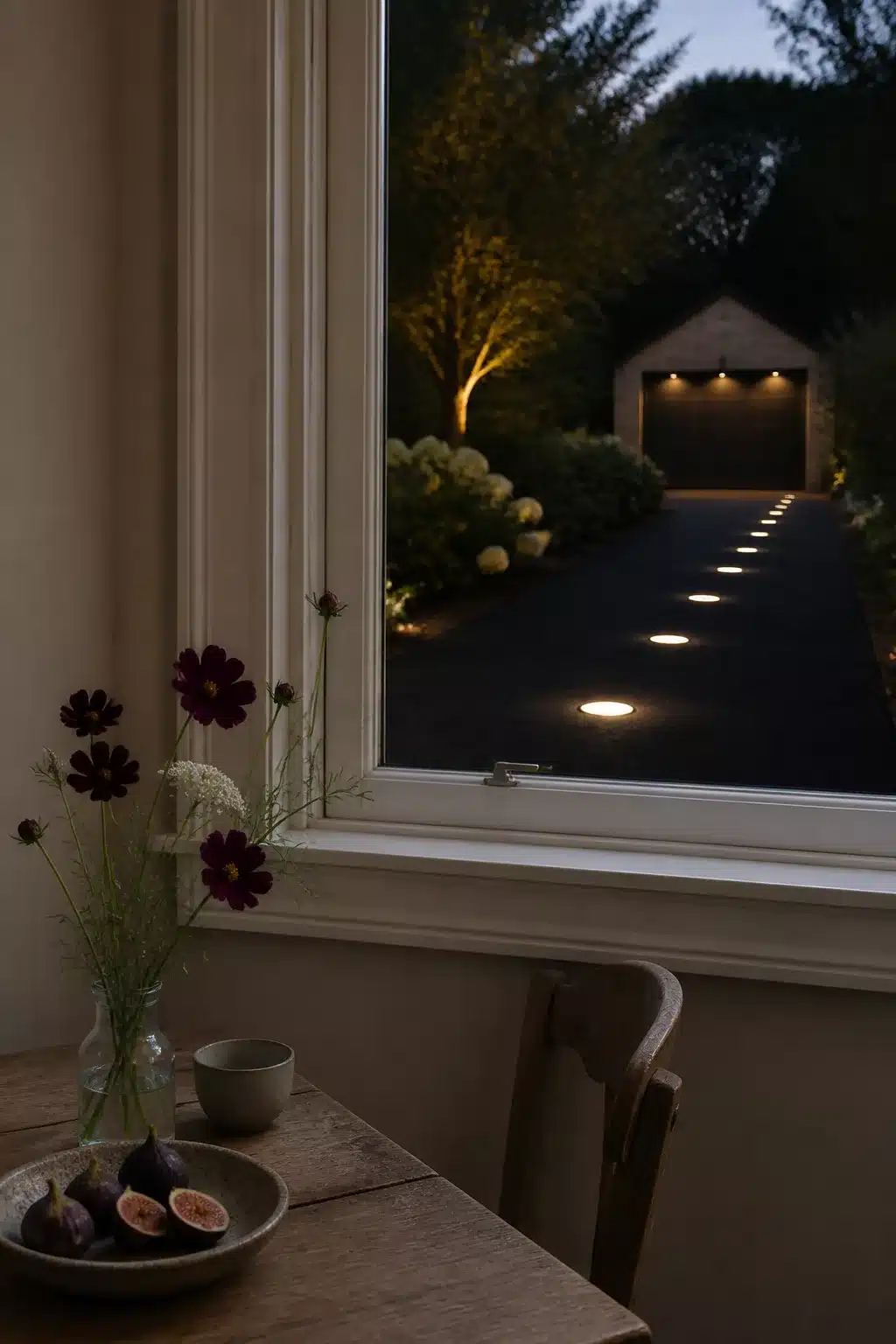 Recessed in-ground driveway lighting ideas with flush asphalt lights glowing at dusk toward a garage