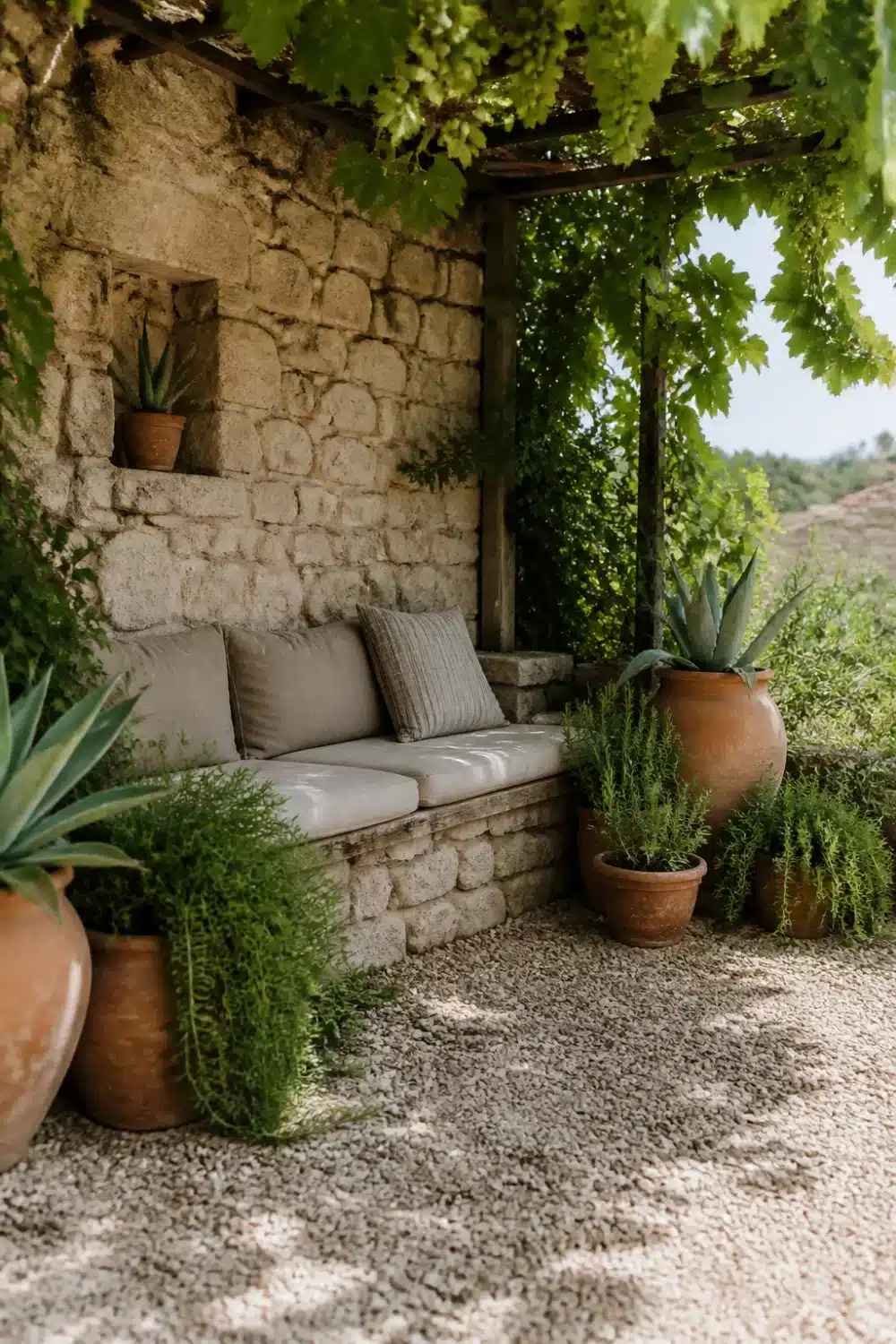 Built-in stone bench with vine canopy and terracotta pots in a Mediterranean garden design
