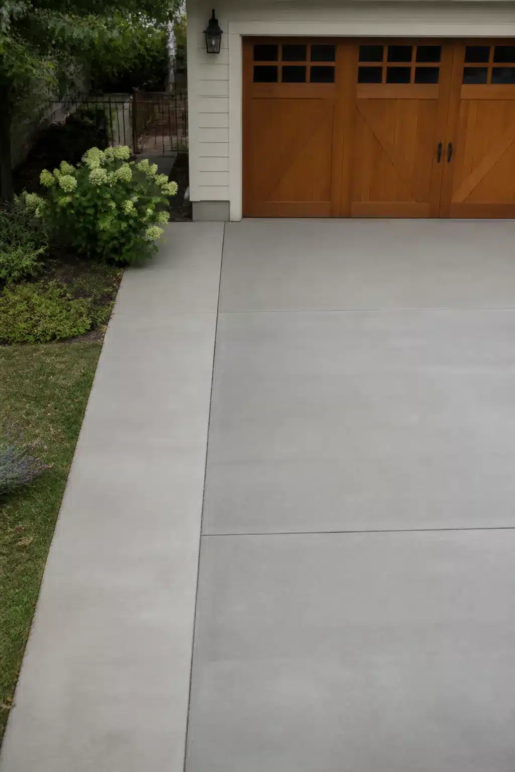 Widen driveway idea using two-tone broom-finish concrete panels with clean control joints and cedar garage door
