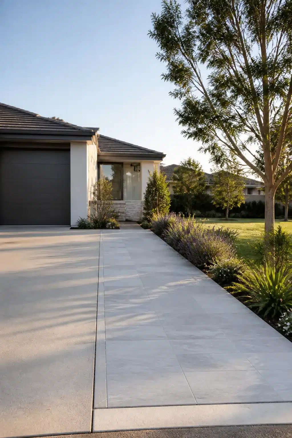 Light gray large-format porcelain tile widened driveway with planted border — widen driveway ideas