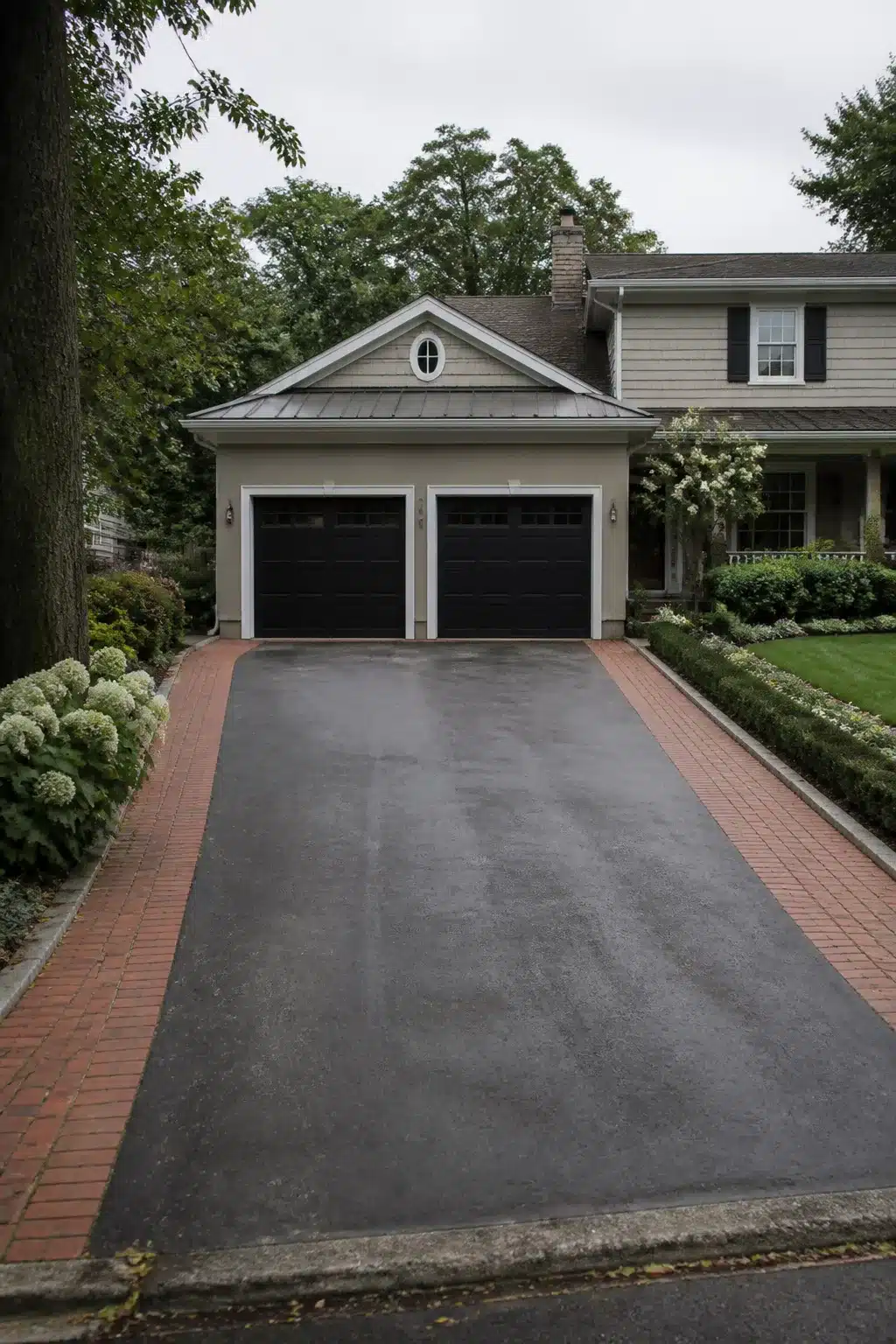 Widen driveway idea with red brick paver border framing a wide asphalt center and lush front yard landscaping.