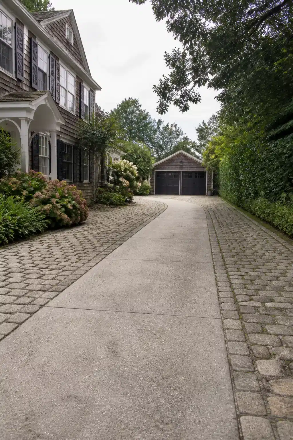 Widen driveway ideas with tumbled cobblestone border extensions flanking a smooth concrete center strip